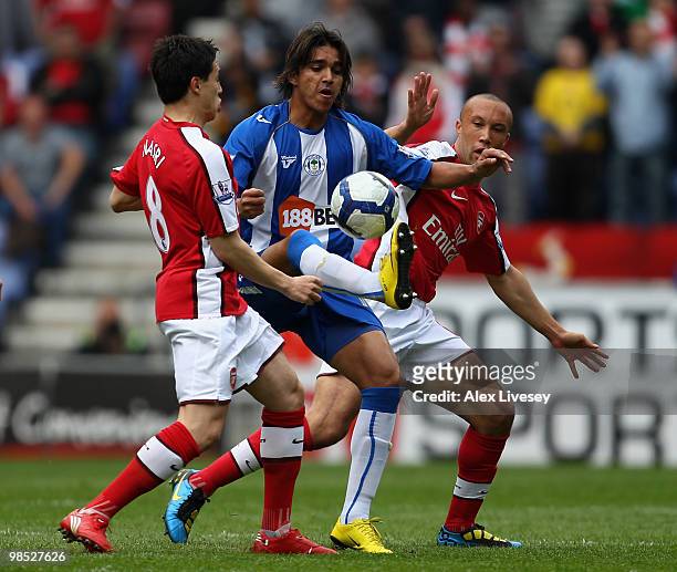 Marcelo Moreno of Wigan Athletic holds off Samir Nasri and Mikael Silvestre of Arsenal during the Barclays Premier League match between Wigan...