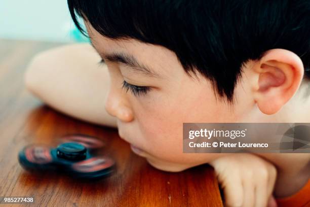 young boy playing with fidget spinner - peter lourenco stock-fotos und bilder