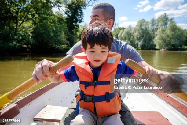 a father teaching his son to row a boat - peter lourenco stock-fotos und bilder