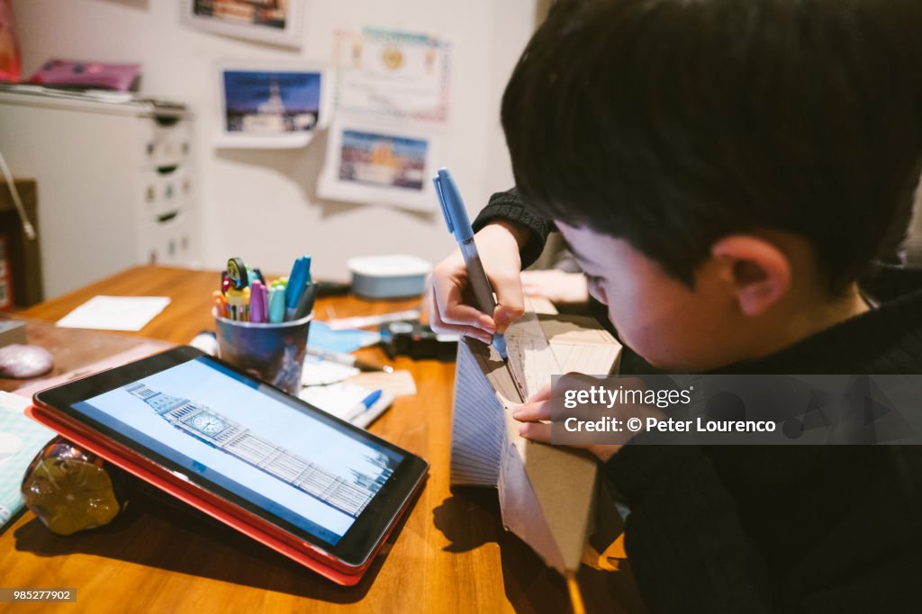 Boy crafting a clock tower out of cardboard