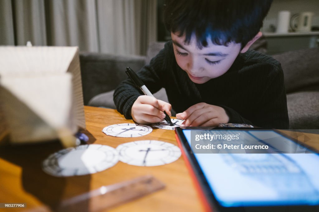 Boy crafting a clock tower out of cardboard