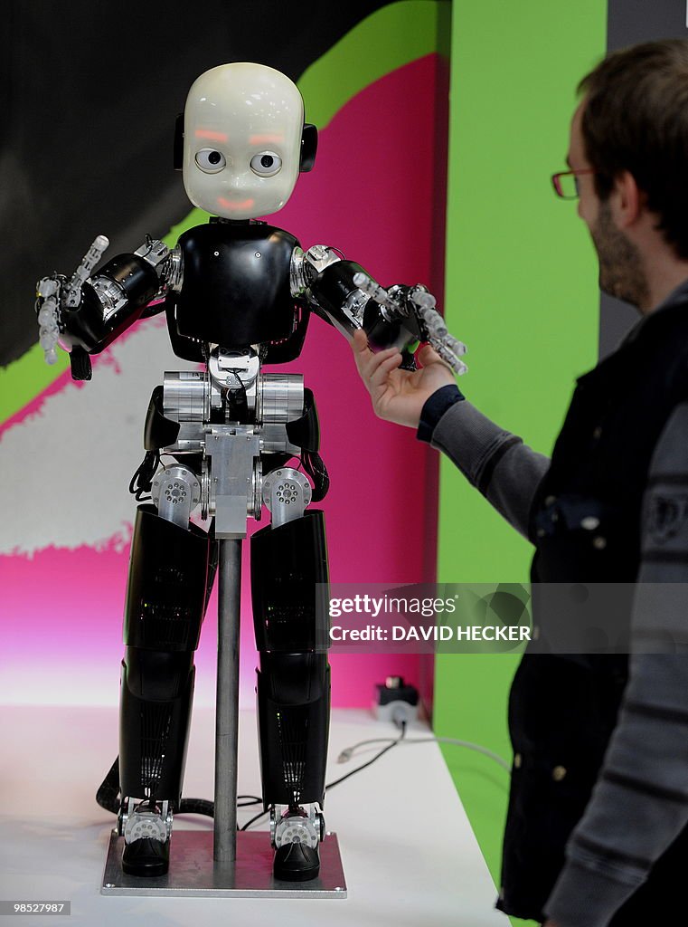 A man touches the robot "iCub" at the st