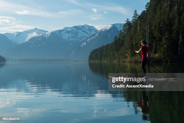 vrouw peddelen op een prachtig bergmeer - british columbia coast mountains stockfoto's en -beelden