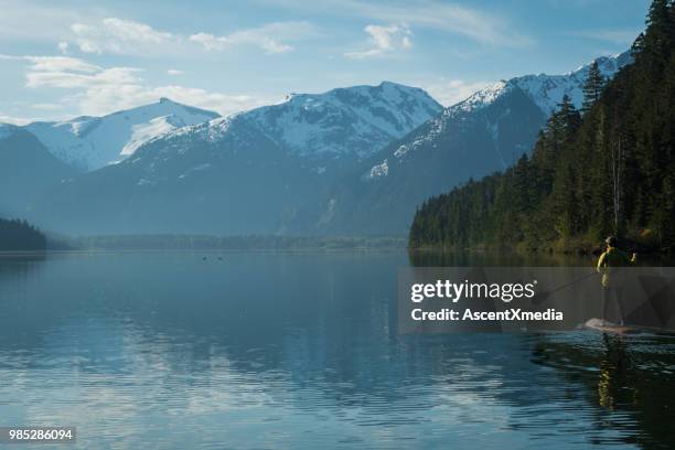 vrouw peddelen op een prachtig bergmeer - british columbia coast mountains stockfoto's en -beelden