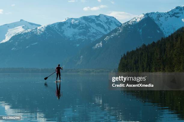 vrouw peddelen op een prachtig bergmeer - british columbia coast mountains stockfoto's en -beelden