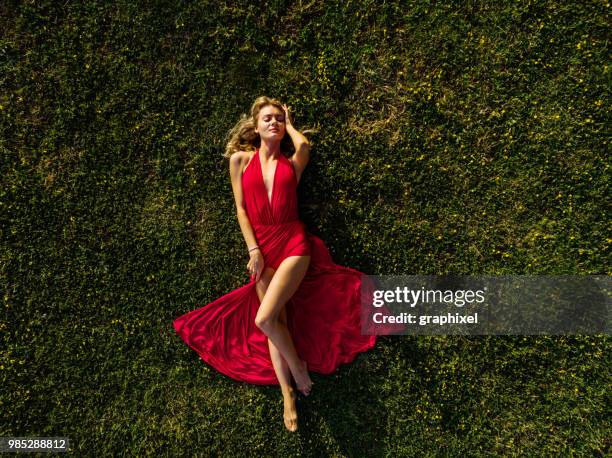 beautiful woman lying on green grass - form fitted dress stock pictures, royalty-free photos & images