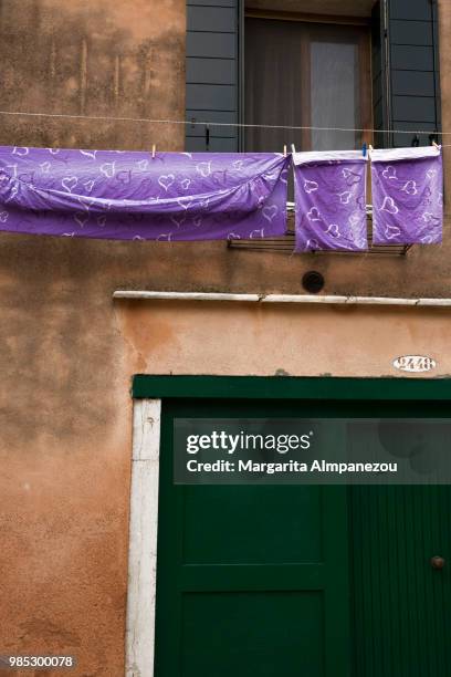 purple bed sheets drying outside of a window in venice - almpanezou stockfoto's en -beelden