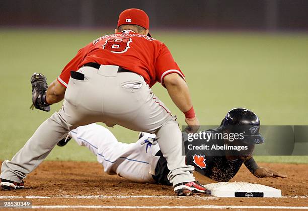 Vernon Wells of the Toronto Blue Jays slides safe into first with Kendry Morales of the Los Angeles Angels of Anaheim missing the tag during a MLB...