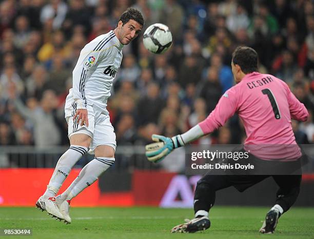 Gonzalo Higuain of Real Madrid tries to shoot past Cesar Sanchez of Valencia during the La Liga match between Real Madrid and Valencia at Estadio...