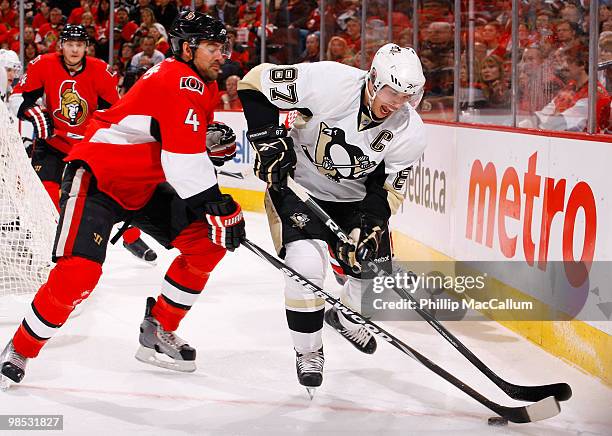 Sidney Crosby of the Pittsburgh Penguins tries to control the puck down low while fighting off the close checking of Chris Phillips of the Ottawa...