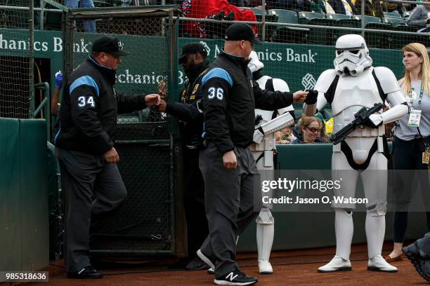 Umpires Ryan Blakney and Sam Holbrook are greeted by Star Wars storm troopers upon entering the field before the game between the Oakland Athletics...