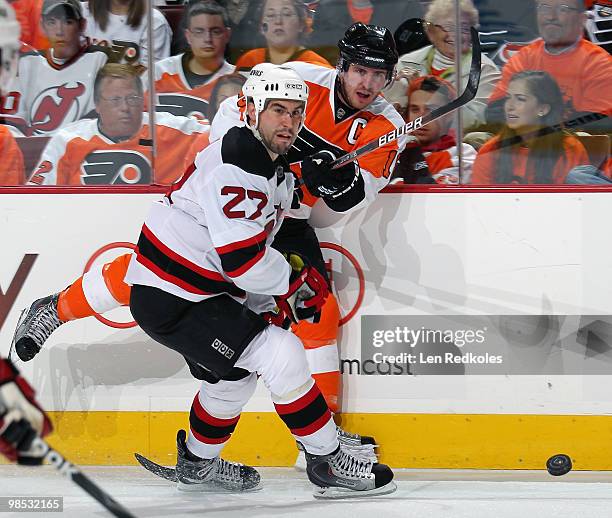 Mike Mottau of the New Jersey Devils checks Mike Richards of the Philadelphia Flyers into the boards as he releases the puck in Game Three of the...