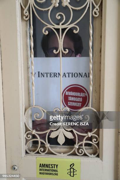 Aron Demeter, press officer for Amnesty International Hungary, poses on June 27, 2018 with a poster that was placed on the street door of Amnesty's...