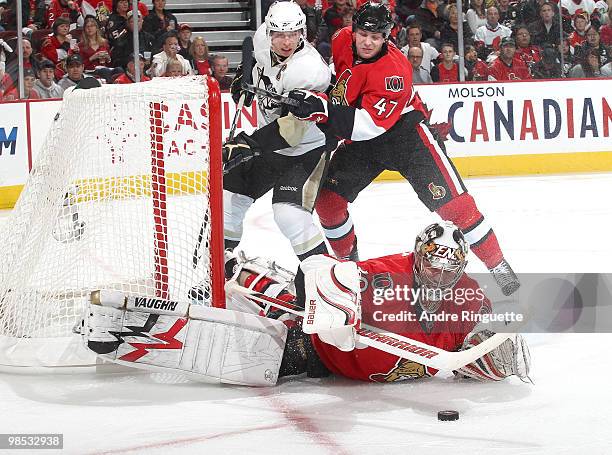 Brian Elliott of the Ottawa Senators dives for the loose puck as teammate Zack Smith stops Sidney Crosby of the Pittsburgh Penguins from getting to...