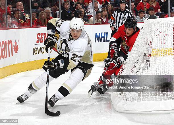 Alexei Ponikarovsky of the Pittsburgh Penguins stickhandles the puck on a wraparound attempt as Andy Sutton of the Ottawa Senators follows behind the...