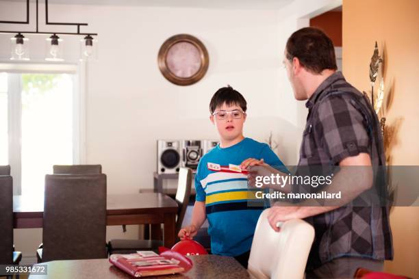 Father helping her son of 12 years old with Autism and Down Syndrome in daily lives using visual aids