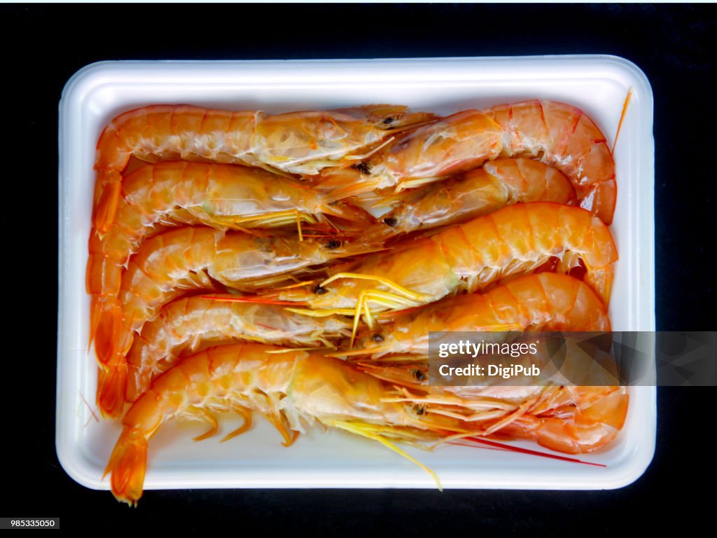 Argentine red shrimp, ten in white plastic tray on black background