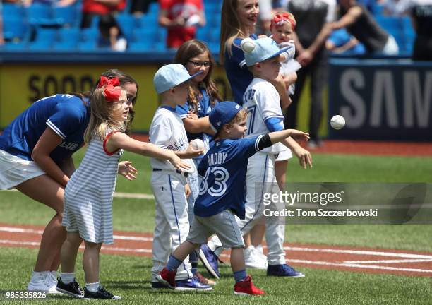 The kids of J.A. Happ of the Toronto Blue Jays and John Axford throw out the first pitch on Fathers Day before the start of MLB game action against...