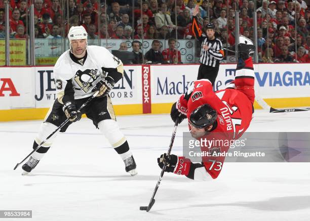 Jarkko Ruutu of the Ottawa Senators goes airborne while stickhandling the puck after being tripped as Bill Guerin of the Pittsburgh Penguins looks on...
