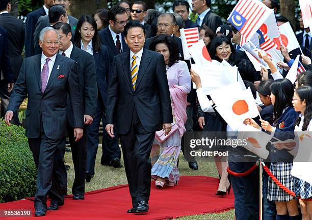 Malaysian Prime Minister Najib Tun Razak walks with Japanese Prime Minister Yukio Hatoyama beside school children waving national flags to attend the...