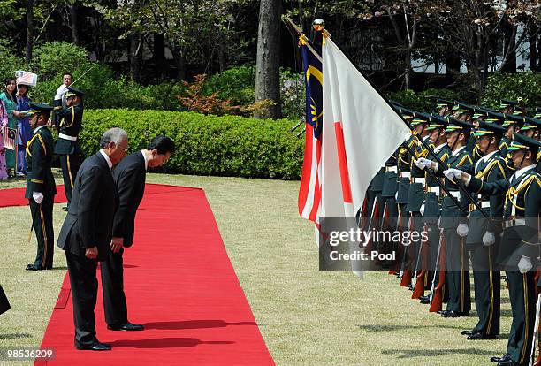 Malaysian Prime Minister Najib Tun Razak and Japanese Prime Minister Yukio Hatoyama bow before their national flags while reviewing the honour guard...