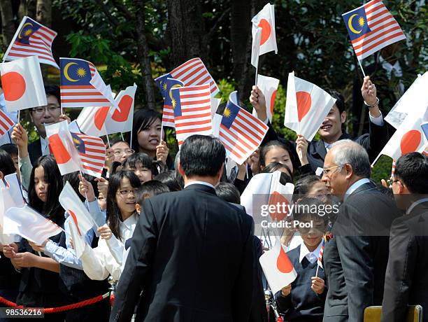 Malaysian Prime Minister Najib Tun Razak walks in front of school children waving national flags during the welcoming ceremony at Hatoyama's official...