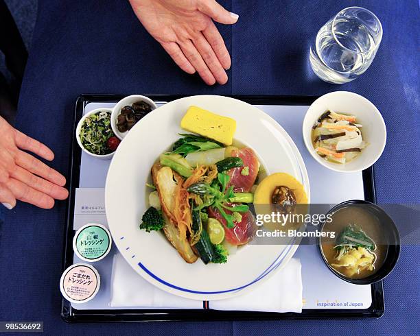 Flight attendant demonstrates the serving of a meal during the unveiling of All Nippon Airways Co.'s new branded service "Inspiration of Japan"...