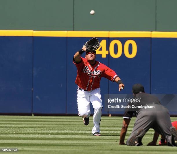 Melky Cabrera of the Atlanta Braves makes a catch in front of Umpire Damien Beal during the game against the Colorado Rockies at Turner Field on...