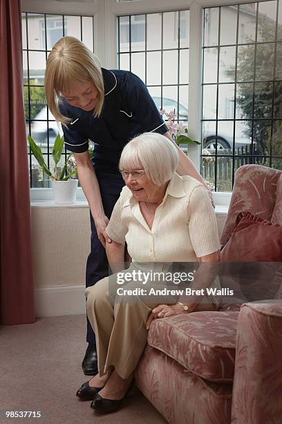 elderly woman being helped into a chair by a carer - moving up to seated position stock pictures, royalty-free photos & images