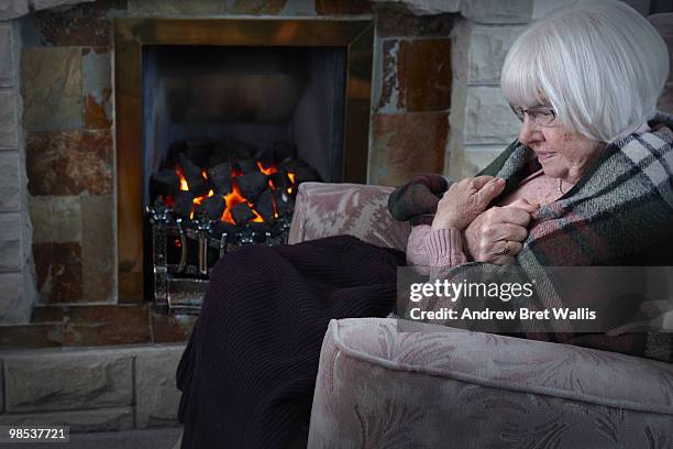 elderly woman trying to keep warm by the fireside - blanket stock pictures, royalty-free photos & images