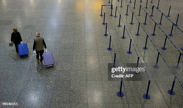 Couple walk with their luggage through an empty departures hall at Gatwick airport in southern England, on April 19 following the closure of the...