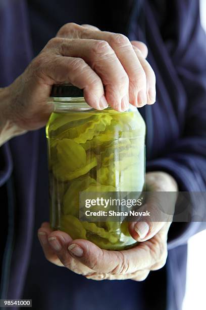 senior woman opens pickle jar - shana novak stock pictures, royalty-free photos & images