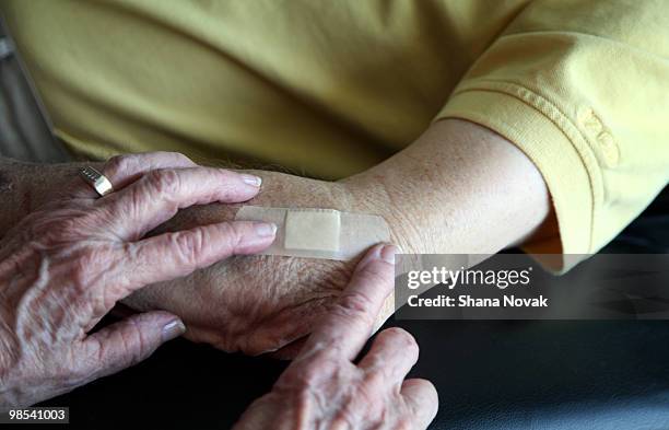 senior woman applies bandage to senior man - shana novak stock pictures, royalty-free photos & images