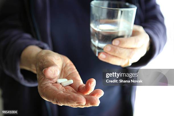 senior woman holds water and pills - shana novak stockfoto's en -beelden