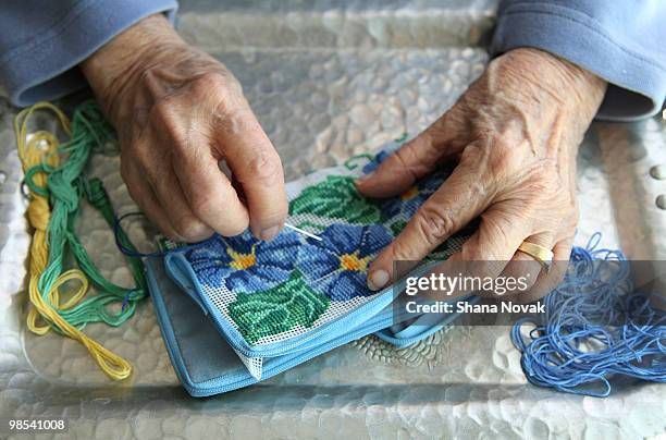 senior woman using needle for needlepoint - shana novak stockfoto's en -beelden