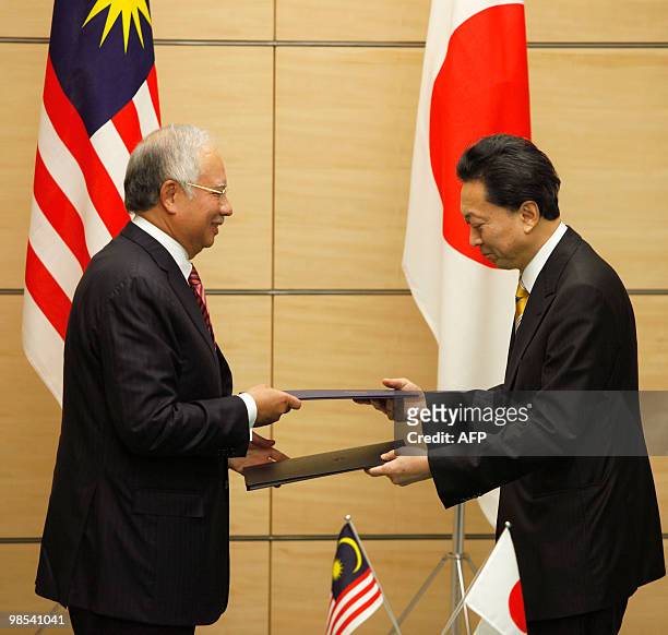 Malaysia's Prime Minister Najib Razak and Japanese Prime Minister Yukio Hatoyama exchange documents during a signing ceremony at the latter's...