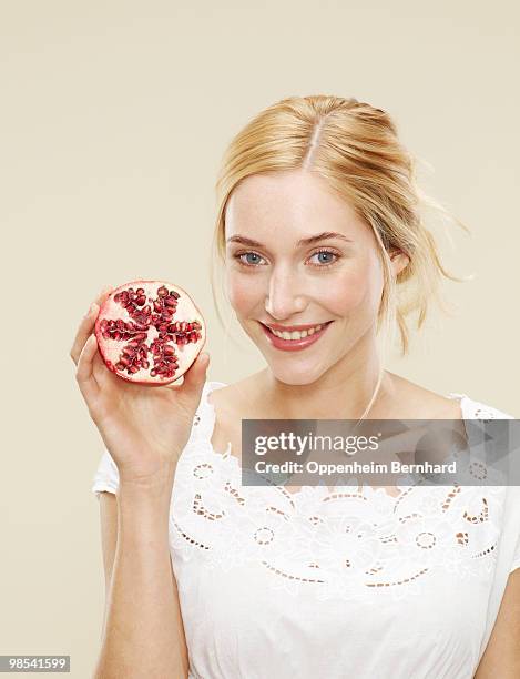 woman smiling and holding pomegranate - 5 am tag stock-fotos und bilder