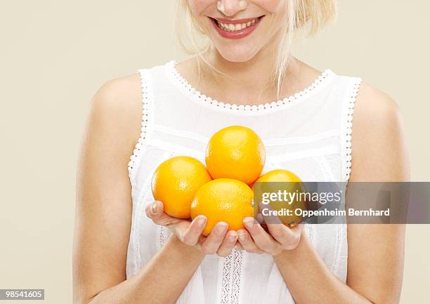 young woman smiling and holding oranges - 5 am tag stock-fotos und bilder