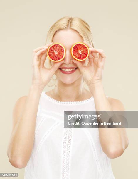 woman holding cut blood oranges over eyes - vitamin c stock-fotos und bilder