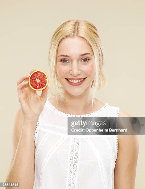 woman smiling and holding half a blood orange - 5 am tag stock-fotos und bilder
