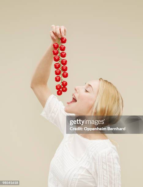 woman holding a bunch of tomatoes to eat - woman with mouth open stock pictures, royalty-free photos & images