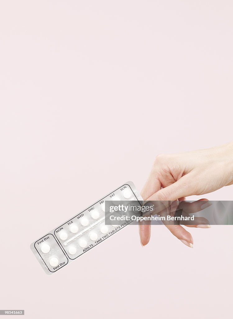 Female hand holding anti pregnancy pills