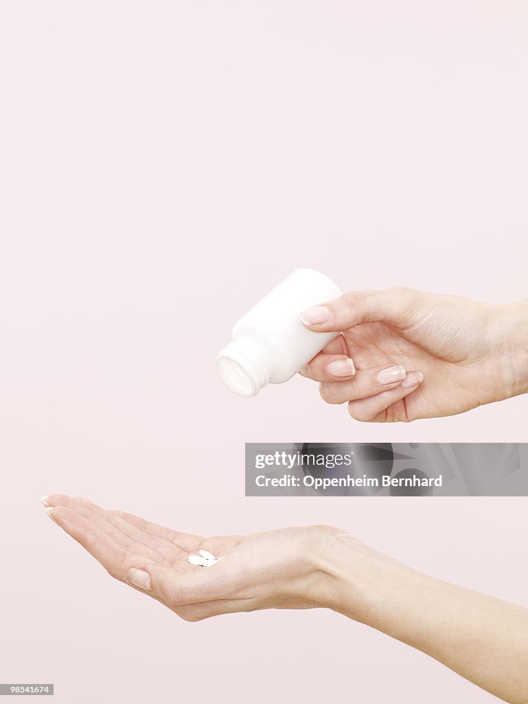 Female hands pouring out tablets into palm