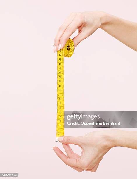 female hands holding out measuring tape - centimeter stockfoto's en -beelden