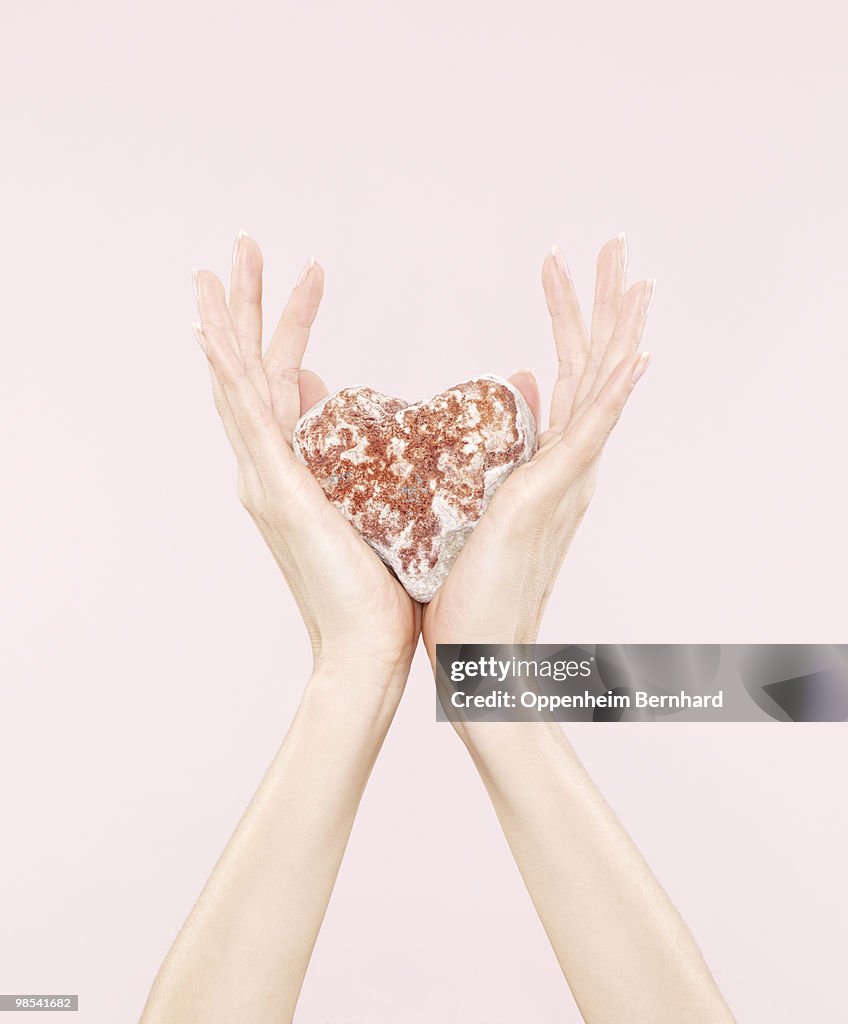 Female hands holding heart shaped stone