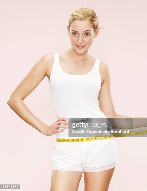 woman holding measuring tape around waist - woman measuring tape stock pictures, royalty-free photos & images