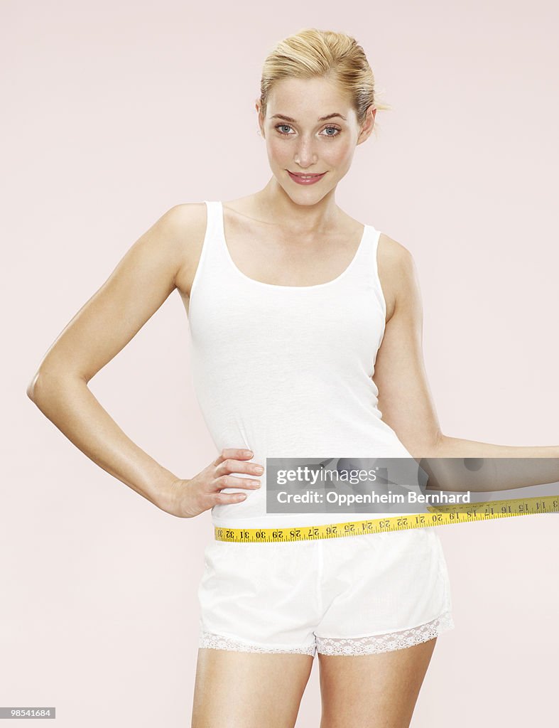 Woman holding measuring tape around waist