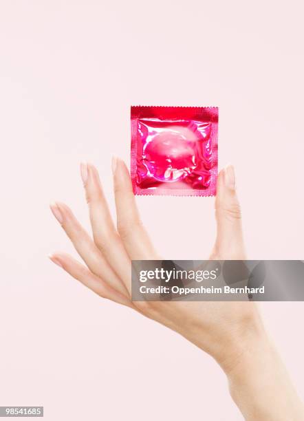 female hand holding sealed condom packet - condoms stock pictures, royalty-free photos & images