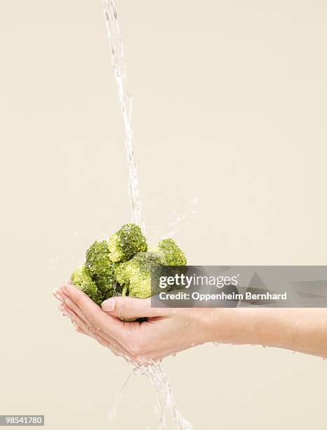 holding brocolli with water splashing on - 5 am tag stock-fotos und bilder