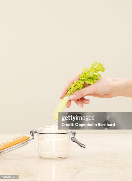 female hand dipping celery into pot of humous - 5 am tag stock-fotos und bilder